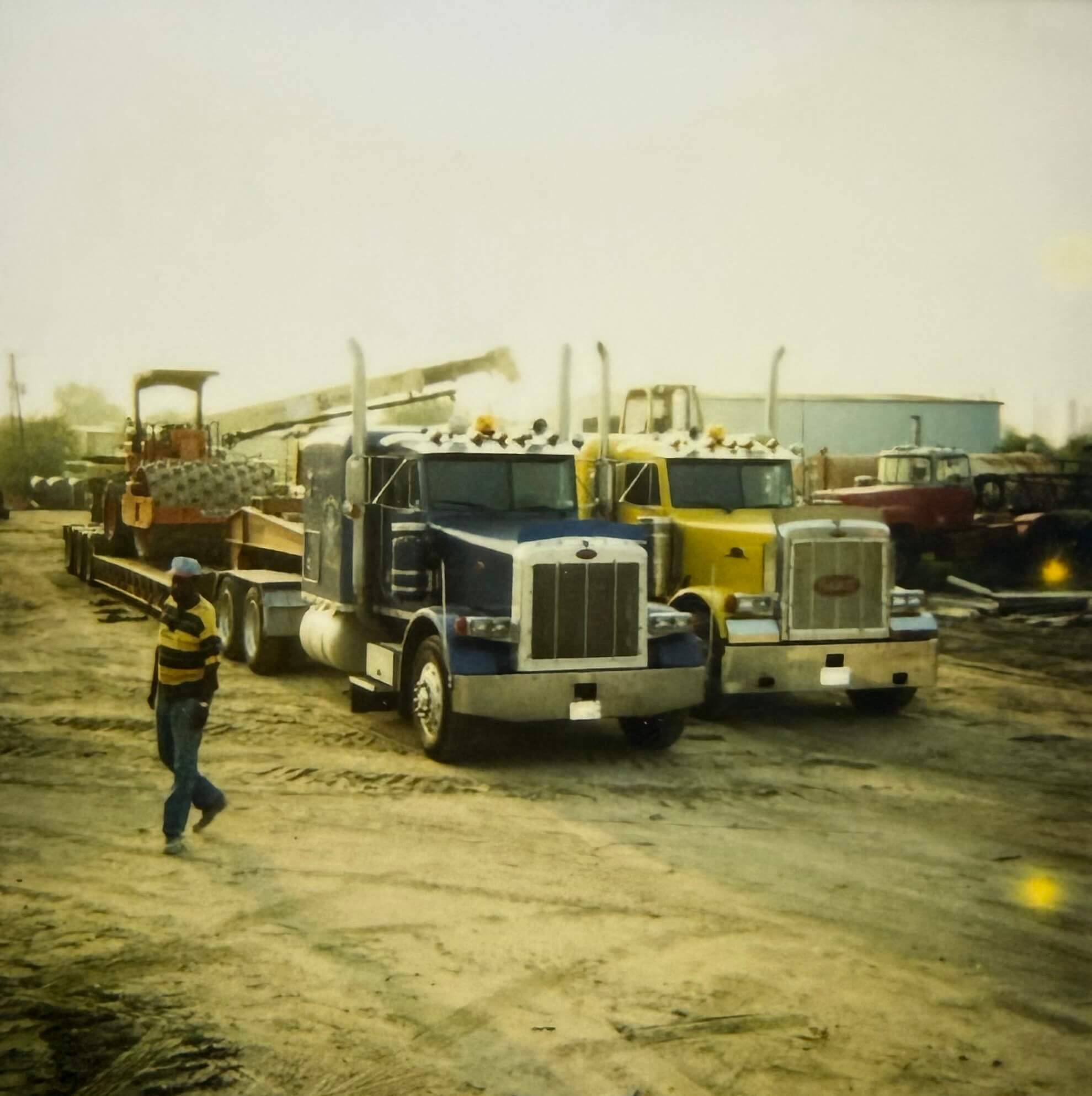 Trucks lined up at a construction site with a worker nearby.